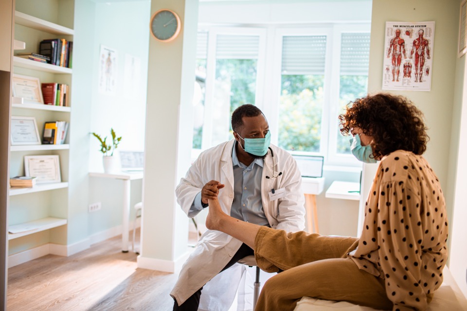 A doctor checks a patient's leg in a bright clinic room